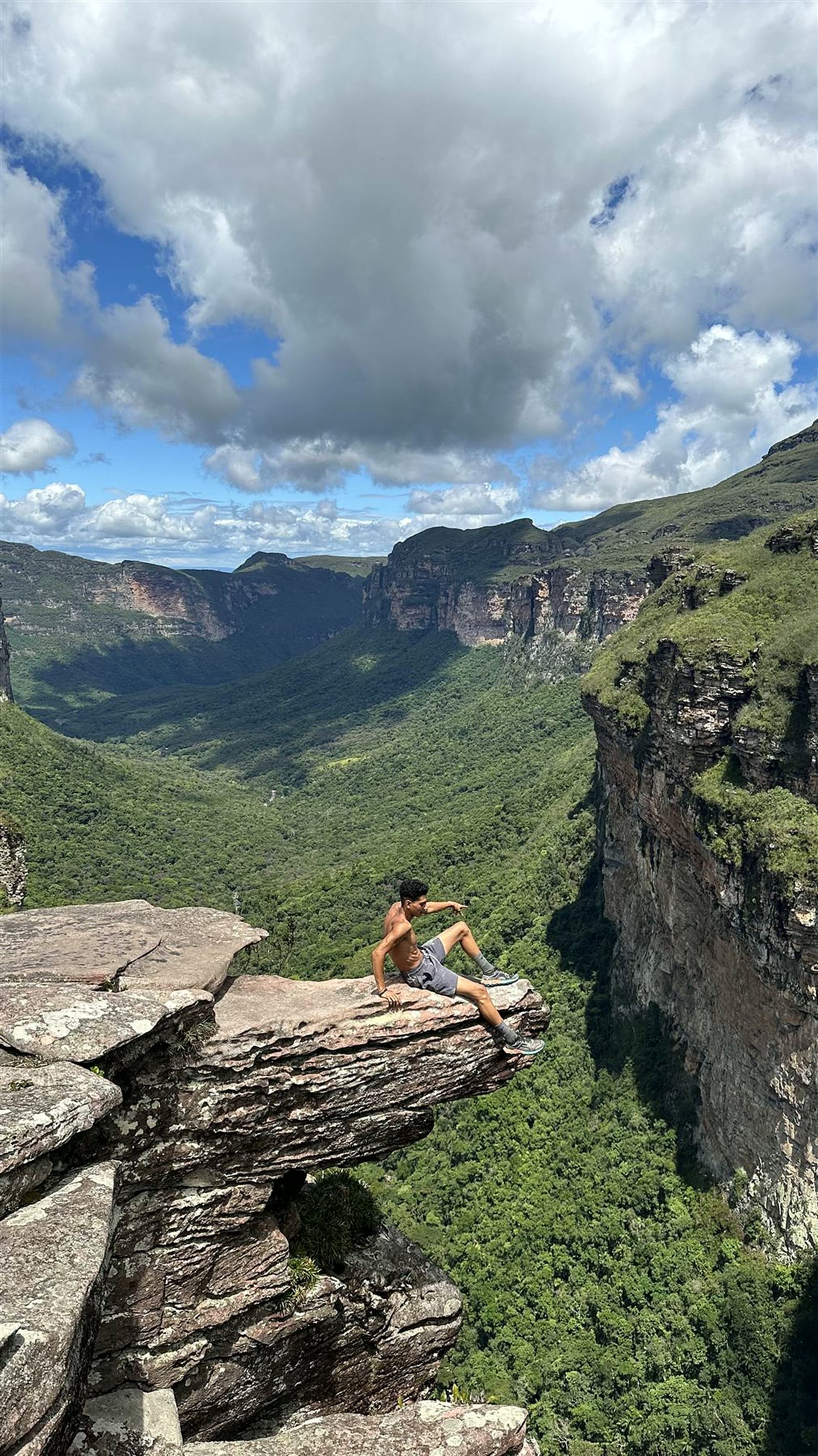 Trilheiro sentado na pedra suspensa sobre o Vale do Pati, no mirante do Cachoeirão